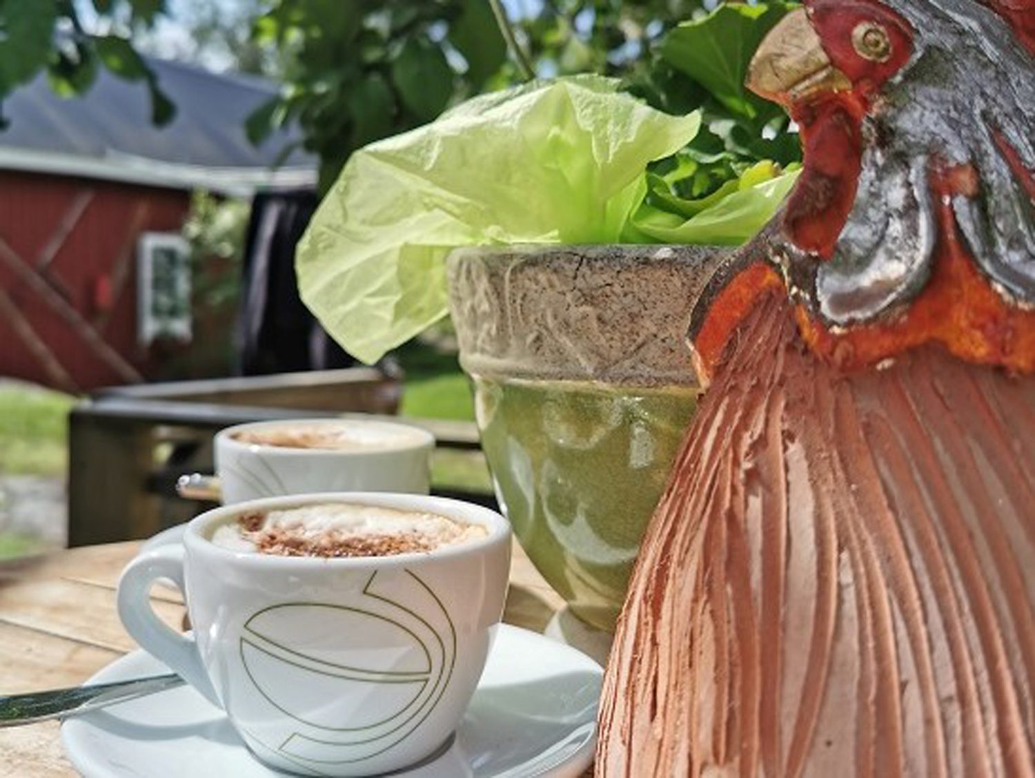 En bild på ett bord på nära håll, på bordet finns två små tallrikar med koppar på och vid sidan om en höna gjord av porslin.